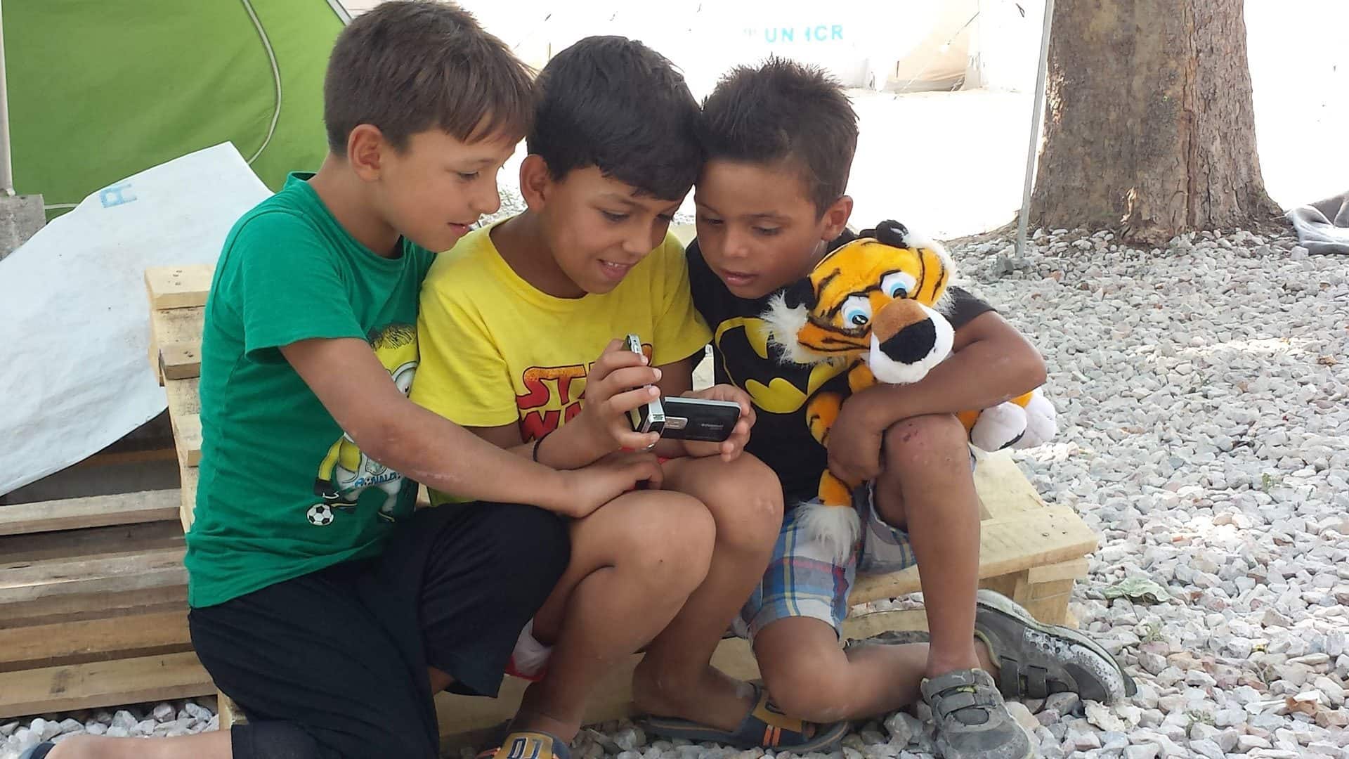 Three migrant boys looking at the photos they took